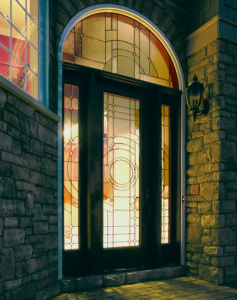 A front entry door with decorative glass patterns and a curved window at the top is shown from the outside of a home