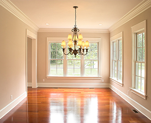 An empty dining room with a chandelier hanging from the ceiling. Double-hung windows line the walls.