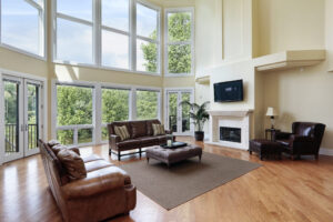 A large room with high ceilings is brightly lit with natural light that floods through walls of picture windows